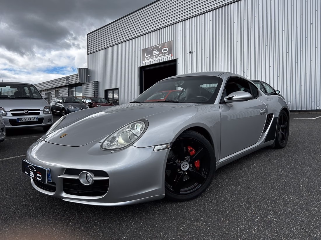 Porsche Cayman grise photographiée devant le hangar du Garage LBO à Lempdes